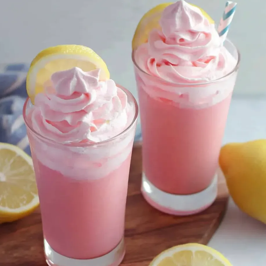 Pink lemonade in two glasses on a table topped with lemon slices.