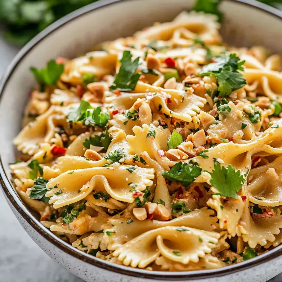 A bowl filled with pasta, veggies, and nuts.