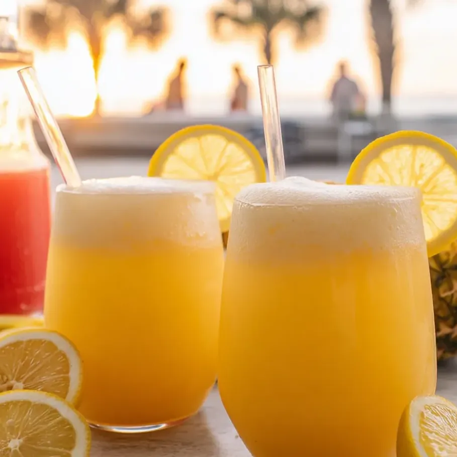 Two glasses of lemonade topped with lemon slices.