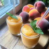 Two glasses of peach juice with mint leaves.