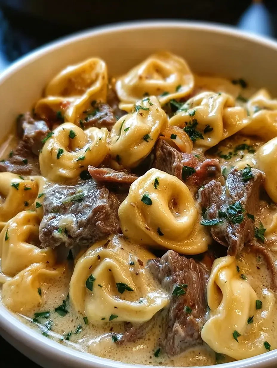 A bowl of cheesesteak tortellini in creamy provolone sauce.