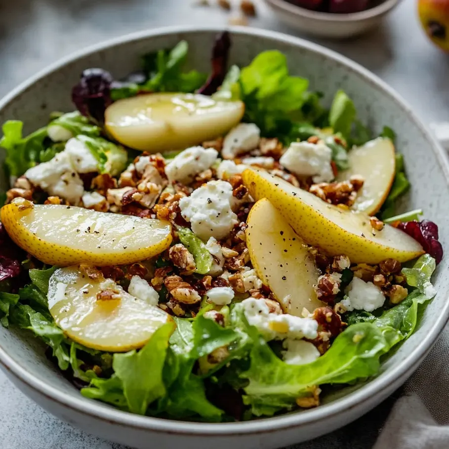 Salad in a bowl with lettuce, pear slices, and feta.