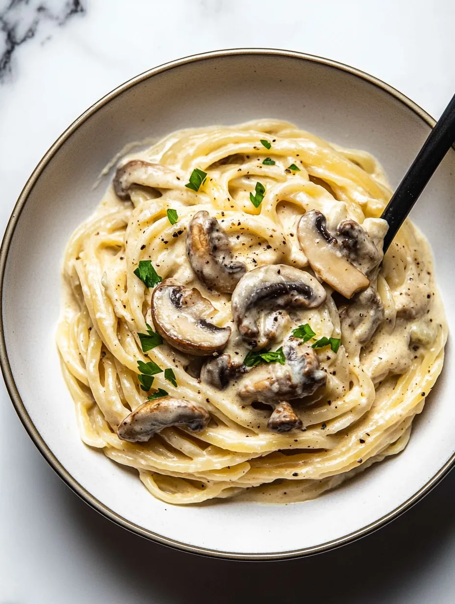 A bowl piled with noodles, mushrooms, and fresh herbs.