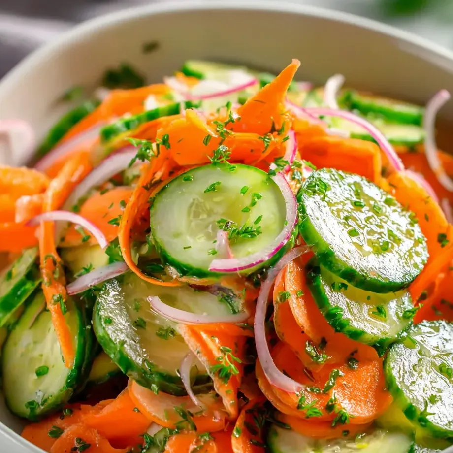 Chopped cucumbers, carrots, and onions in a serving bowl.