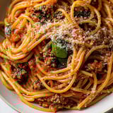 A hearty plate of spaghetti with meat sauce and a topping of cheese.