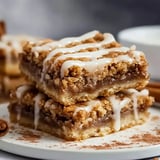 A couple of gooey cinnamon blondies stacked up on a plate.