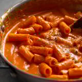A bowl of pasta with red sauce.