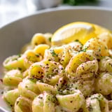 A bowl of pasta with a lemon wedge on top.