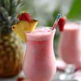 Pink drink in a glass with a pineapple wedge up top.