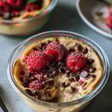 A bowl filled with pancake mix, raspberries, and chocolate chips.